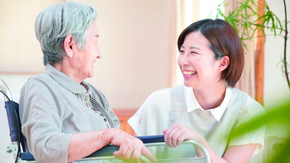 車椅子に座った老婦人と笑顔で会話する女性