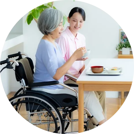 食事する年配女性と介護士