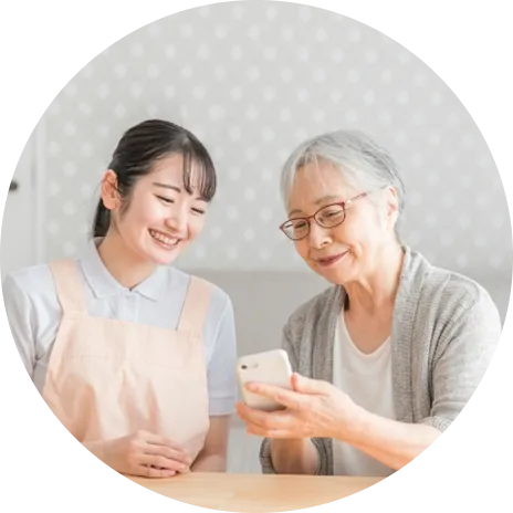 スマホを操作する年配女性と介護士